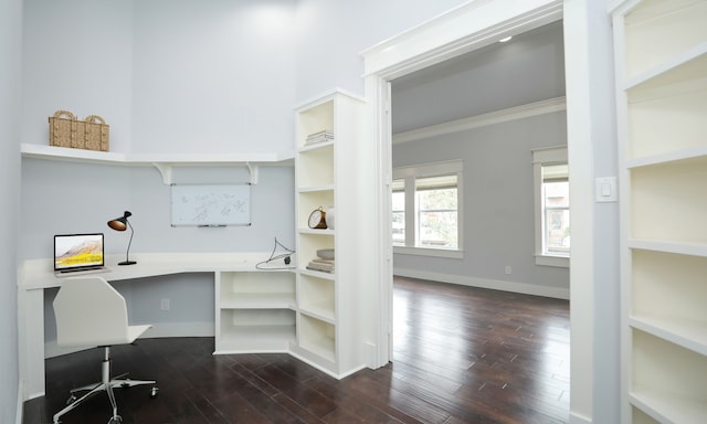 office area featuring crown molding, built in desk, and dark wood-type flooring