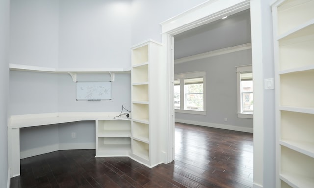 walk in closet featuring built in desk and dark hardwood / wood-style floors