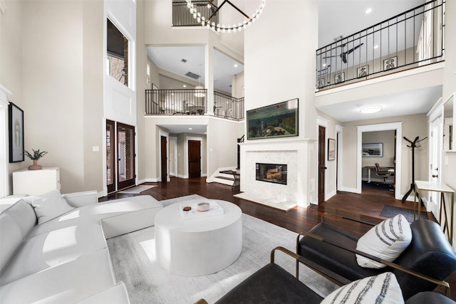 living room featuring dark hardwood / wood-style flooring, a fireplace, a high ceiling, and french doors