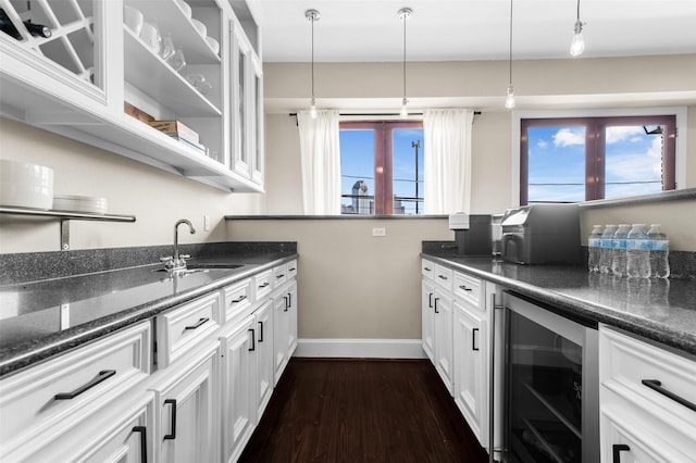 kitchen featuring white cabinets, sink, hanging light fixtures, and beverage cooler