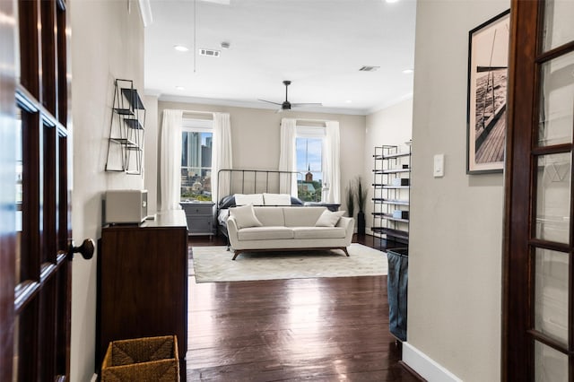 living room featuring ceiling fan, ornamental molding, and dark wood-type flooring