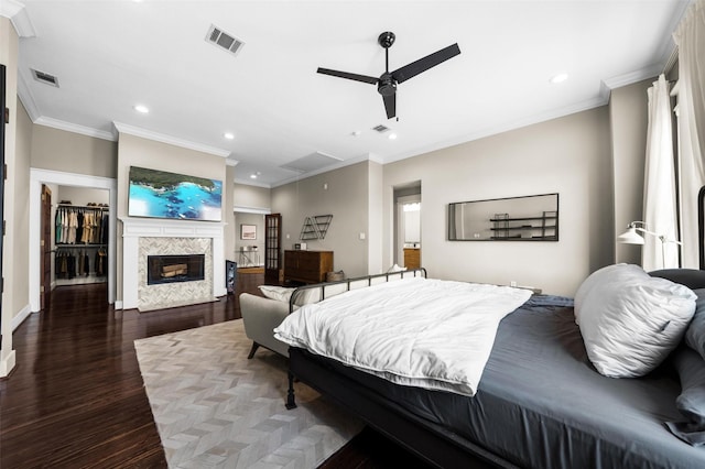 bedroom with a premium fireplace, ceiling fan, dark wood-type flooring, and ornamental molding