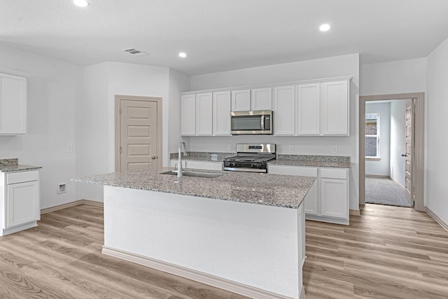 kitchen featuring light wood finished floors, visible vents, a sink, white cabinetry, and appliances with stainless steel finishes