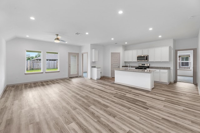 kitchen with recessed lighting, a sink, open floor plan, stainless steel appliances, and white cabinets