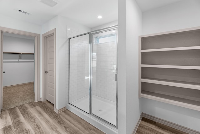 bathroom featuring visible vents, wood finished floors, a stall shower, and a spacious closet