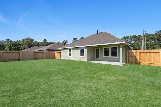 back of house with a shingled roof, a patio, a lawn, and a fenced backyard