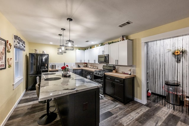 kitchen featuring a kitchen island, dark wood-type flooring, black appliances, white cabinetry, and hanging light fixtures