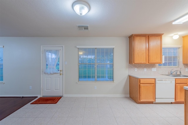 kitchen with tasteful backsplash, white dishwasher, sink, light brown cabinets, and light tile patterned floors