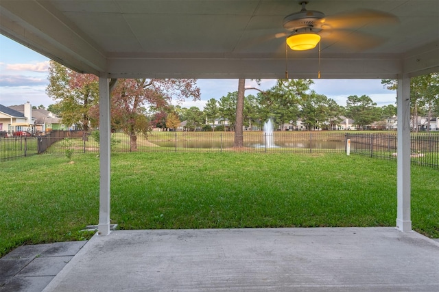 view of yard with ceiling fan, a water view, and a patio