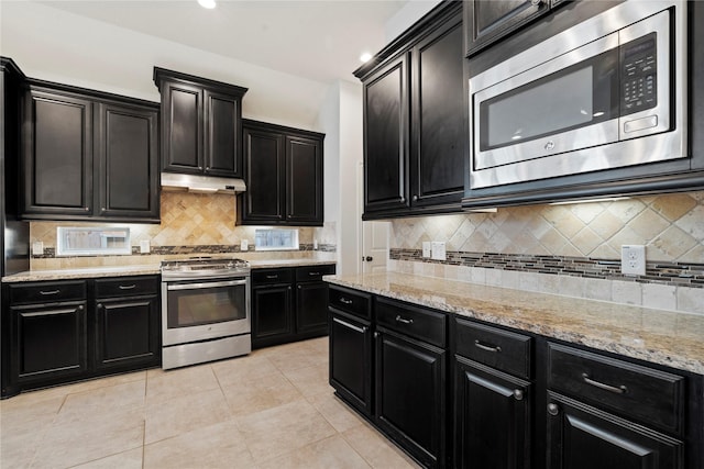 kitchen with light stone countertops, backsplash, stainless steel appliances, and light tile patterned flooring