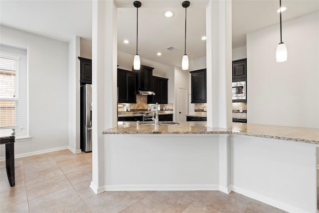 kitchen with backsplash, sink, hanging light fixtures, appliances with stainless steel finishes, and light stone counters