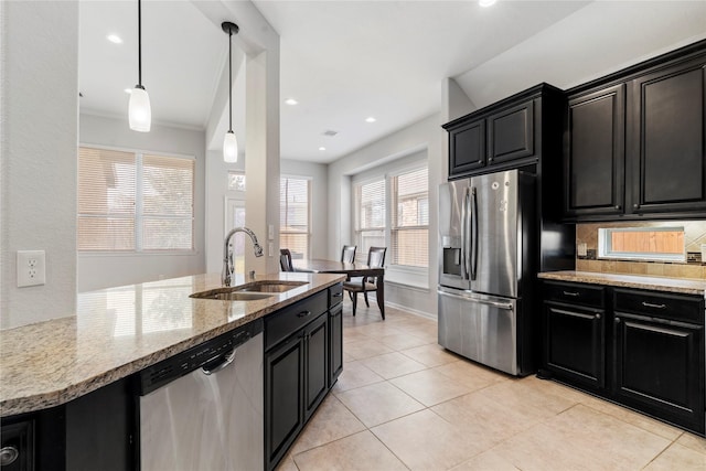 kitchen with pendant lighting, stainless steel appliances, light stone counters, and sink