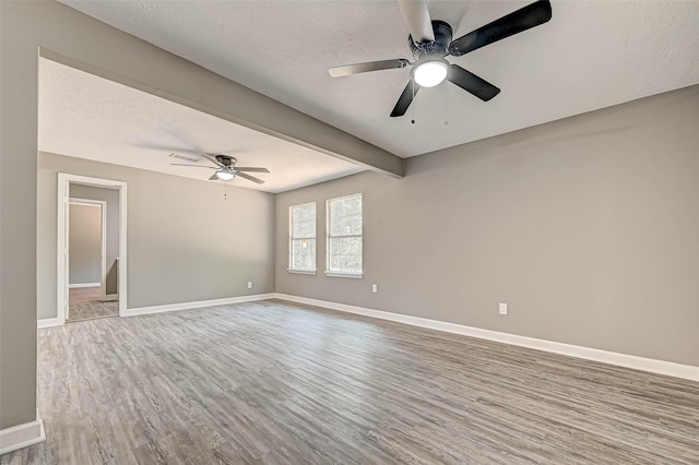 empty room with hardwood / wood-style floors, a textured ceiling, ceiling fan, and beam ceiling