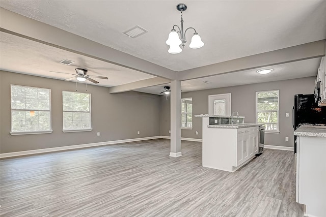 kitchen with light stone countertops, white cabinetry, light hardwood / wood-style floors, and decorative light fixtures