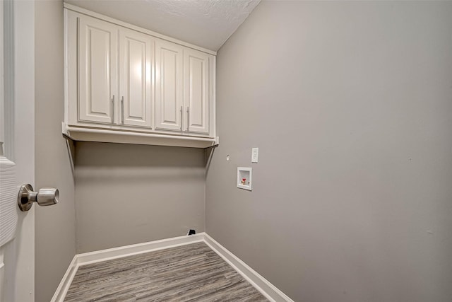 laundry area with hardwood / wood-style floors, cabinets, a textured ceiling, and hookup for a washing machine