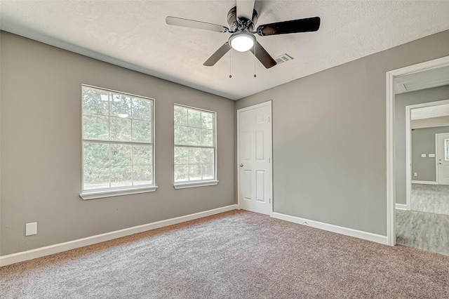 empty room with ceiling fan, carpet floors, and a textured ceiling