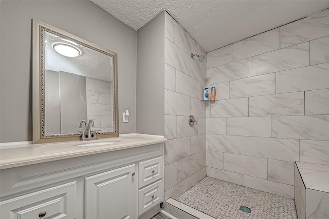 bathroom with vanity, a textured ceiling, and tiled shower