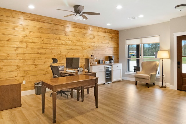 office space featuring light hardwood / wood-style floors, wine cooler, ceiling fan, and wooden walls