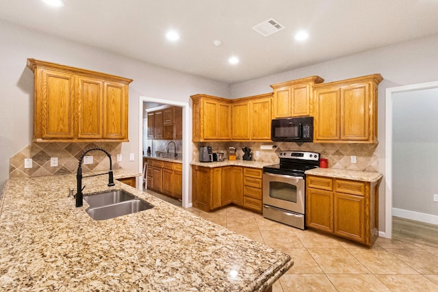 kitchen with decorative backsplash, light tile patterned floors, stainless steel range with electric stovetop, and sink