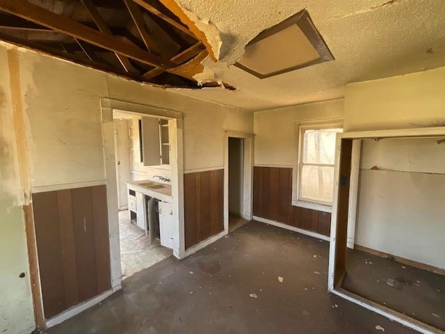 unfurnished bedroom featuring wood walls and a textured ceiling