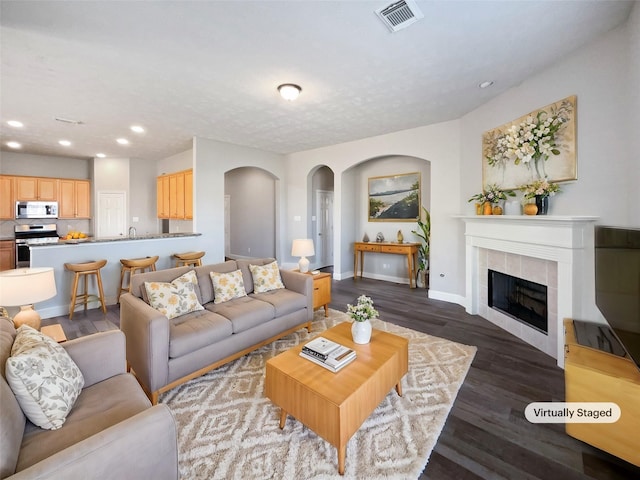 living room featuring dark hardwood / wood-style floors and a tile fireplace