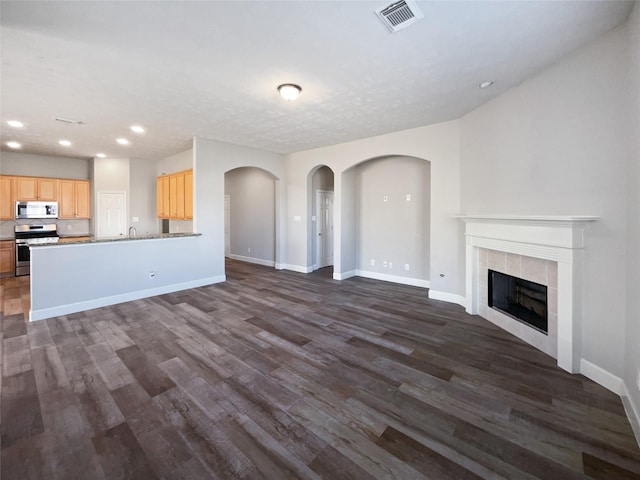 unfurnished living room with a tile fireplace, dark hardwood / wood-style floors, and sink