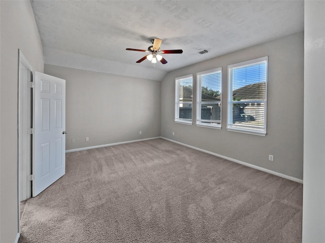 carpeted spare room featuring a textured ceiling, ceiling fan, and lofted ceiling