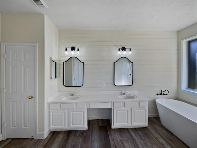 bathroom featuring a tub, wood walls, vanity, and hardwood / wood-style flooring