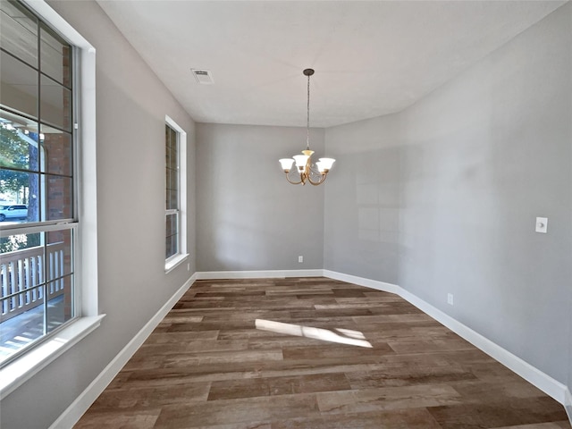 unfurnished dining area with dark hardwood / wood-style flooring and an inviting chandelier