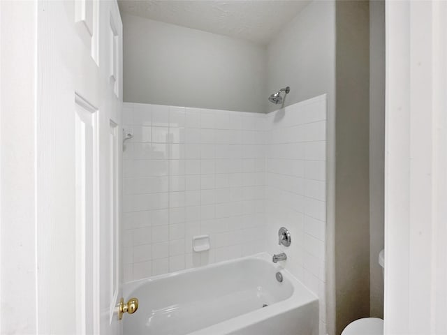 bathroom featuring tiled shower / bath combo, toilet, and a textured ceiling