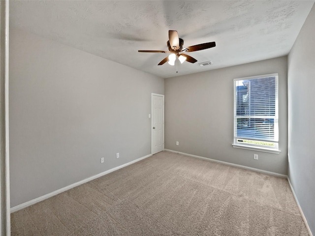 empty room featuring ceiling fan, light colored carpet, and a textured ceiling