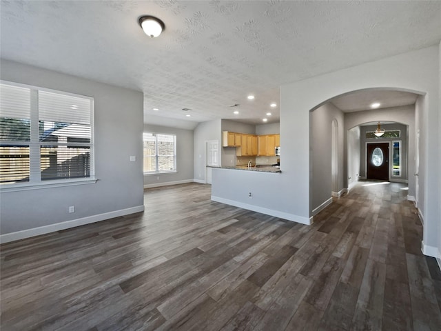 unfurnished living room with a textured ceiling and dark wood-type flooring