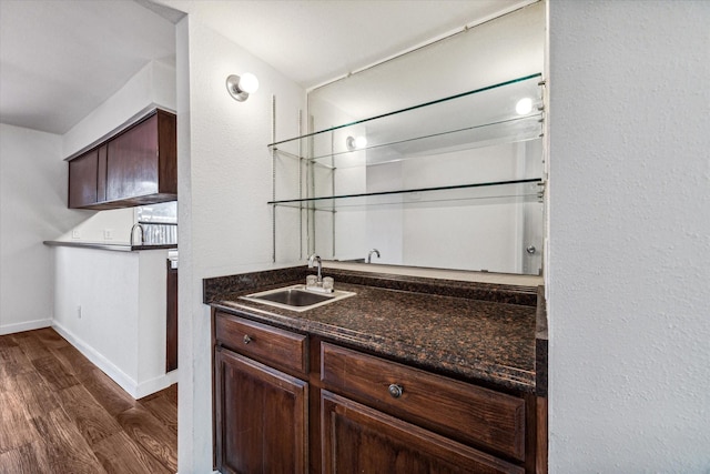 bar with dark brown cabinets, sink, dark stone countertops, and dark hardwood / wood-style floors