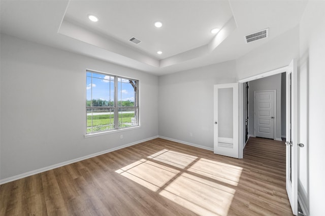 unfurnished bedroom with light hardwood / wood-style floors and a tray ceiling