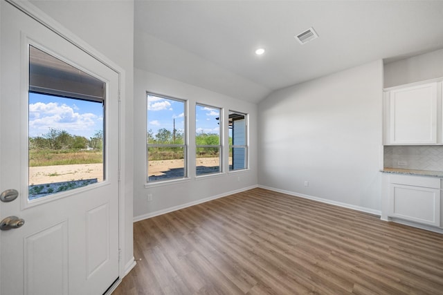 unfurnished dining area with light hardwood / wood-style floors and lofted ceiling