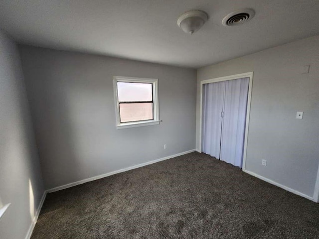 unfurnished bedroom featuring a closet and dark carpet