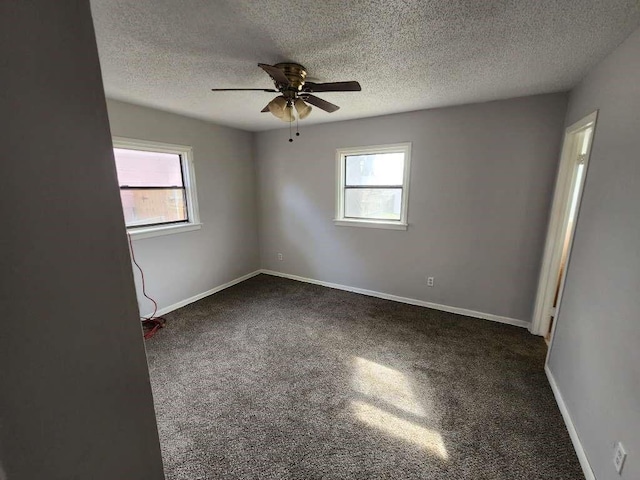 spare room with dark colored carpet, a textured ceiling, and ceiling fan