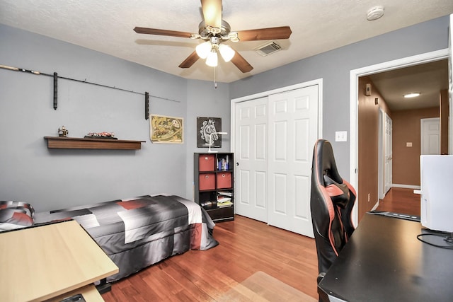 bedroom featuring a textured ceiling, light wood-type flooring, a closet, and ceiling fan