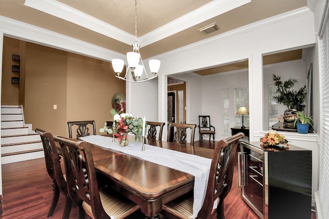 dining room featuring a tray ceiling, crown molding, dark wood-type flooring, and an inviting chandelier