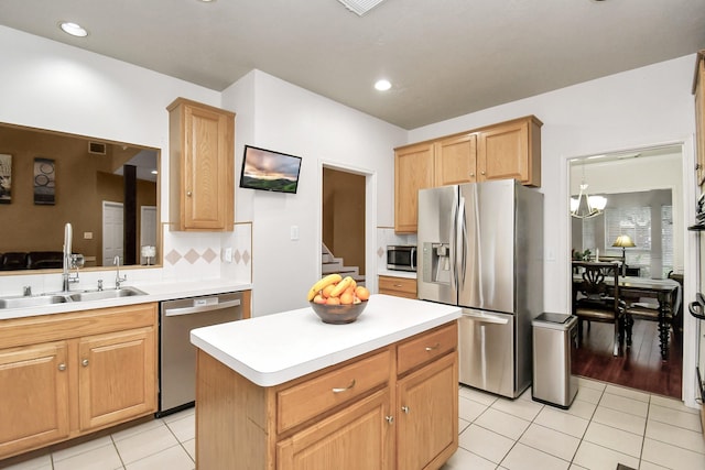 kitchen featuring appliances with stainless steel finishes, sink, an inviting chandelier, a center island, and light tile patterned flooring