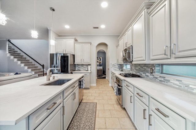 kitchen with appliances with stainless steel finishes, backsplash, sink, light tile patterned floors, and decorative light fixtures