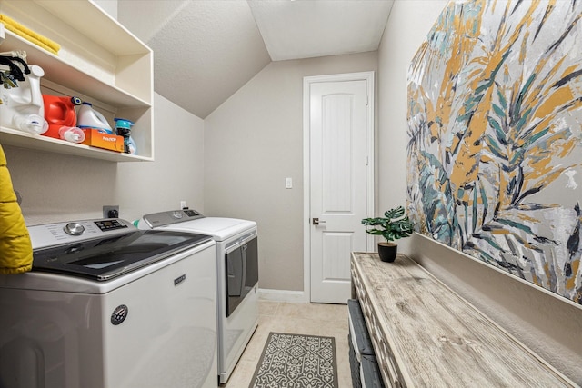 clothes washing area with washer and dryer, light tile patterned floors, and a textured ceiling