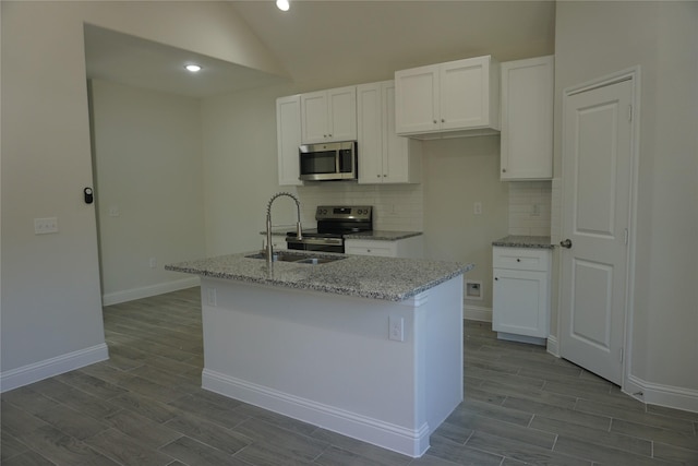 kitchen with a center island with sink, white cabinets, stainless steel appliances, and vaulted ceiling