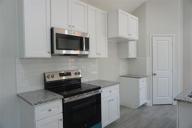 kitchen with stainless steel appliances, white cabinetry, light hardwood / wood-style floors, and light stone counters