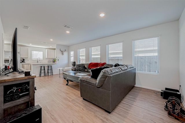 living room featuring sink and light hardwood / wood-style flooring