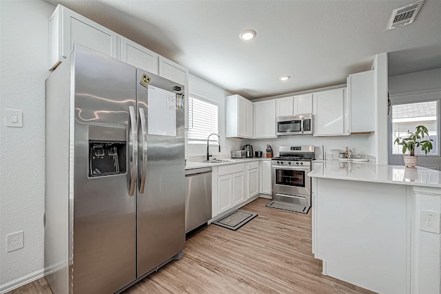 kitchen with white cabinetry, light wood-type flooring, sink, and appliances with stainless steel finishes