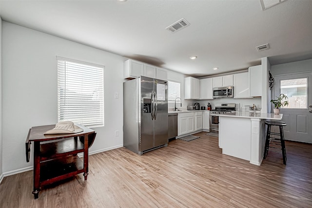 kitchen with white cabinets, a kitchen breakfast bar, stainless steel appliances, and a wealth of natural light