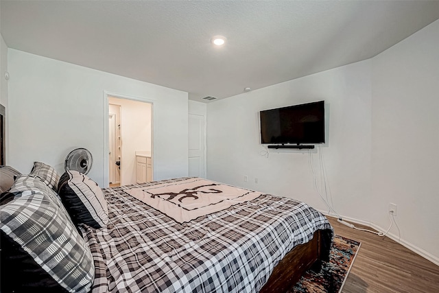 bedroom featuring a textured ceiling, dark hardwood / wood-style flooring, and ensuite bathroom