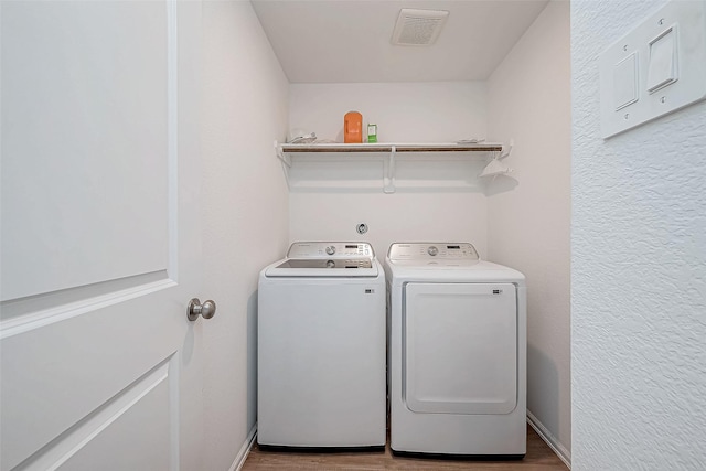 laundry area with independent washer and dryer and light hardwood / wood-style flooring