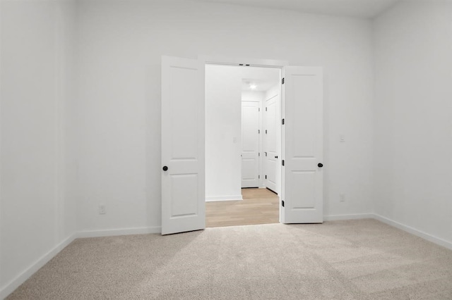 spare room with baseboards and light carpet